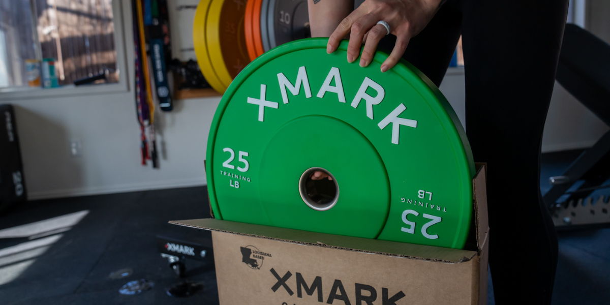 25lb Green XMARK Training Plate being pulled out of a shipment box